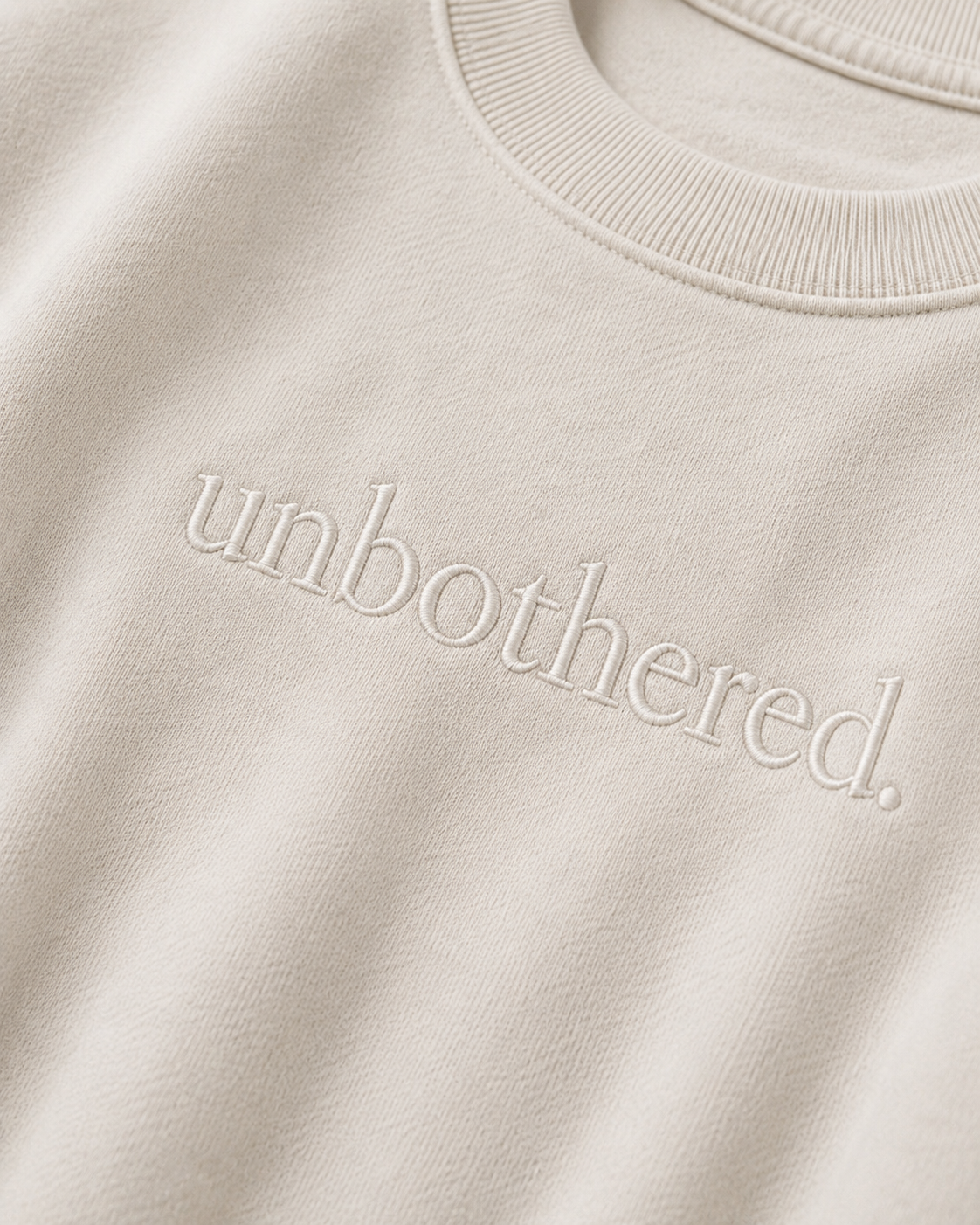 Beige sweatshirt with 'unbothered.' text on a beige background